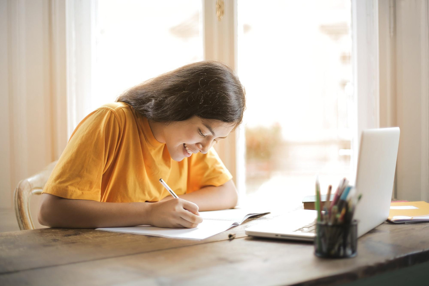 Student writing at a desk